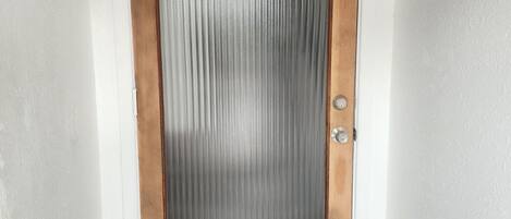 Puerta de madera con un panel de vidrio satinado y una cerradura.