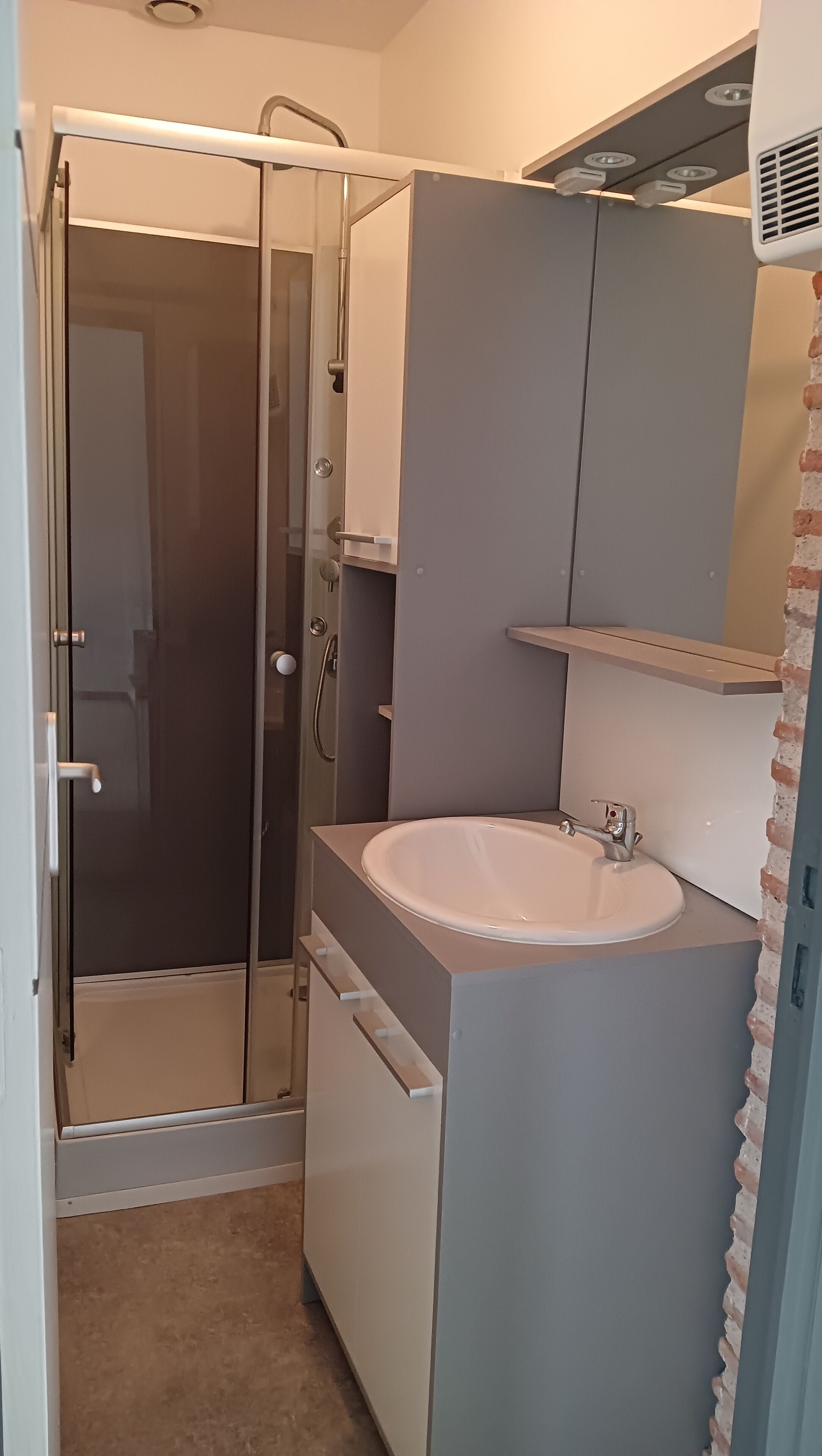 Un bagno con doccia a filo pavimento, lavandino e specchio.