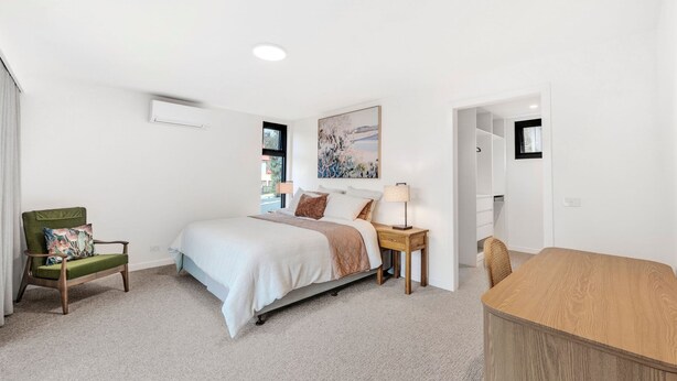 A bedroom with a bed, a chair, a bedside table, and a desk. - Teremoana (Lorne)