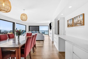 Eine moderne Küche mit weißen Schränken und einem Essbereich mit einem Holztisch und roten Stühlen.