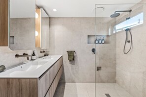 Une salle de bain moderne avec une douche à parois de verre, un meuble-lavabo en bois et un grand miroir.