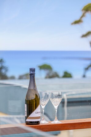 Eine Weinflasche und zwei Gläser auf einem Tisch mit Blick aufs Meer.