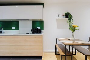 A modern kitchen with a wooden countertop, a coffee machine, and a green backsplash. - Colourful 1BDR Canalside Flat in East London (Greater London)