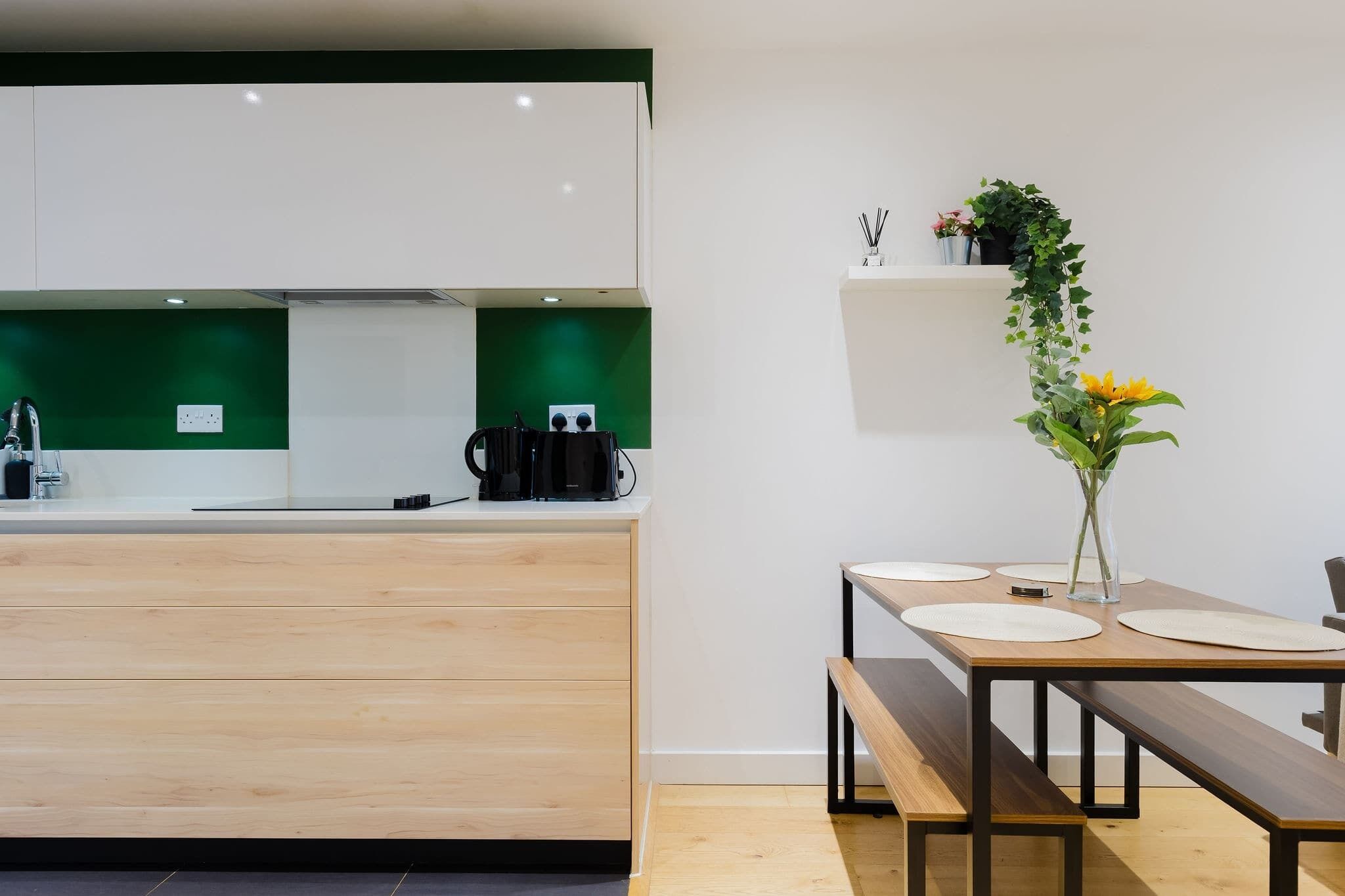 A modern kitchen with a wooden countertop, a coffee machine, and a green backsplash.