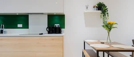 A modern kitchen with a wooden countertop, a coffee machine, and a green backsplash.