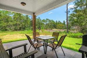An outdoor patio with a table and chairs, surrounded by a grassy area and trees. - Cozy 2 Bedroom Atlas Cottage near Milton FL (Milton)