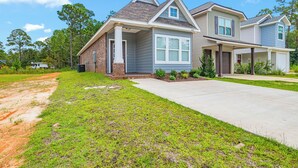 A two-story residential house with a front driveway, a lawn, and a clear sky. - Cozy 2 Bedroom Atlas Cottage near Milton FL (Milton)