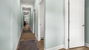 A hallway with a wooden floor, a rug, and a white door. - Cozy 2 Bedroom Atlas Cottage near Milton FL (Milton)