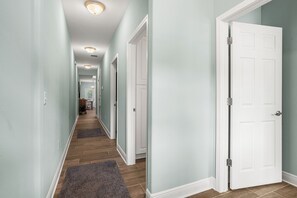 Ein Flur mit Holzboden, Teppich und einer weißen Tür.