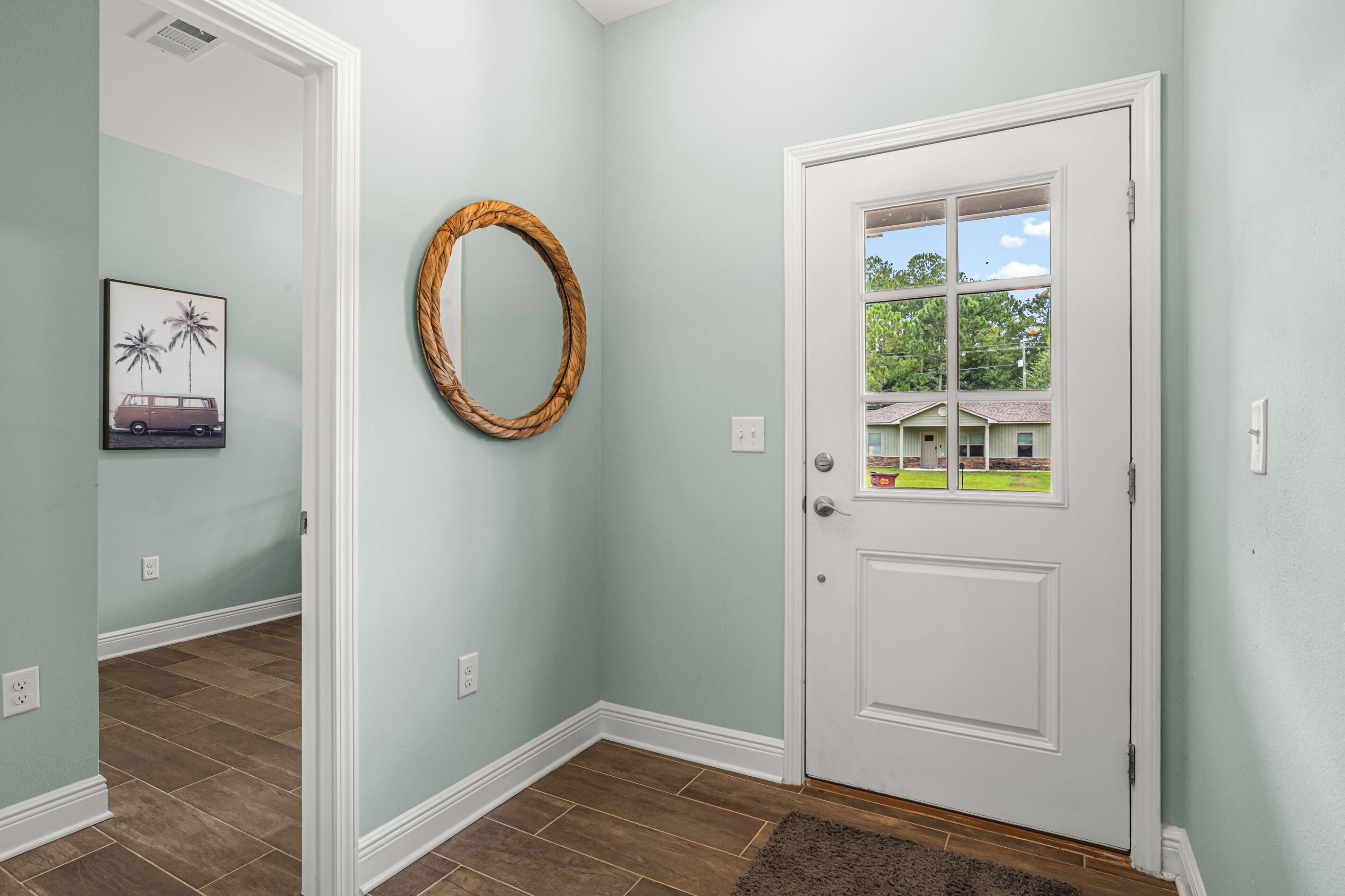 A hallway with a white door, a framed picture, and a woven wall decoration.