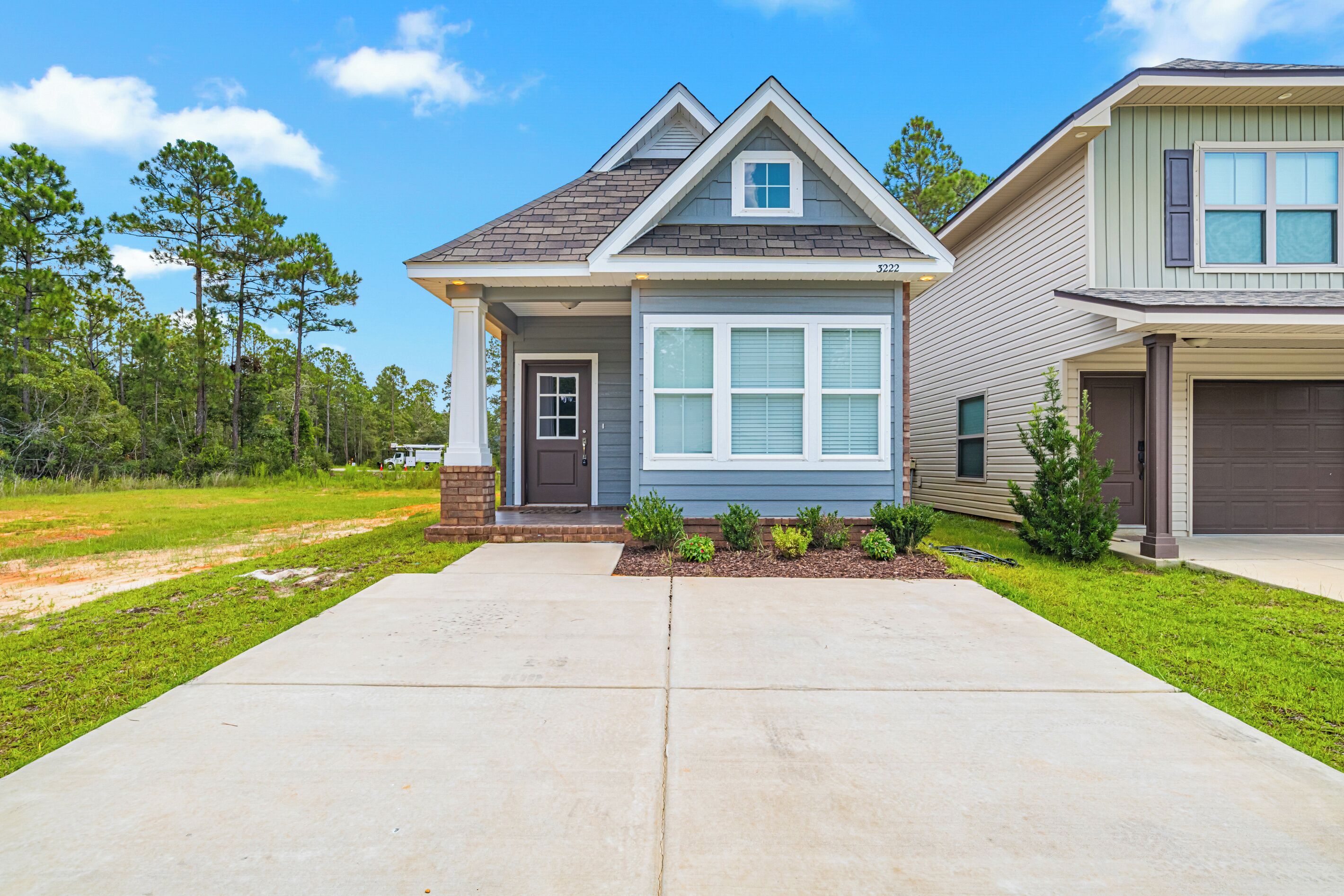 A residential house with a front porch, a garage, and a well-maintained lawn.