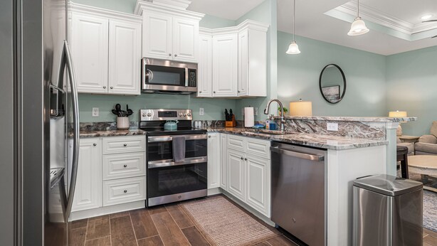 A modern kitchen with white cabinetry, stainless steel appliances, a marble countertop, and a built-in dishwasher. - Cozy 2 Bedroom Atlas Cottage near Milton FL (Milton)