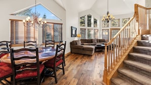 A spacious living area with a dining table, wooden flooring, and a staircase. - Castle Peak Retreat | Scenic Mountain Escape (Edwards)