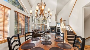 A spacious living room with a large wooden dining table, black chairs, a glass coffee table, and a modern chandelier. - Castle Peak Retreat | Scenic Mountain Escape (Edwards)