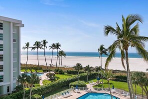 A hotel with a pool, palm trees, and a beach view. - BEACHFRONT 1-bedroom condo in charming Marco Island (Marco Island)