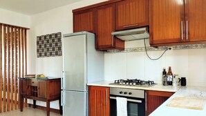 A kitchen with wooden cabinets, a refrigerator, a stove, and a tiled backsplash.