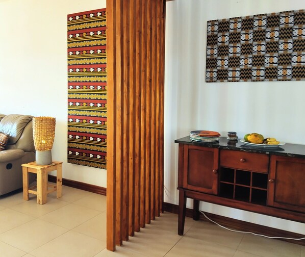 Una sala de estar con un sofá, un mueble de madera, un tapiz decorativo y un taburete pequeño.