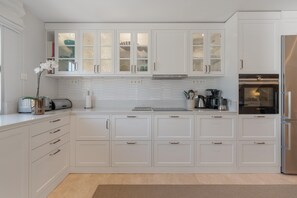 A modern kitchen with white cabinetry, a stainless steel refrigerator, and a built-in oven. - Holiday Home 'Beautiful 4 bedroom Townhouse' with Shared Pool, Wi-Fi and Air Conditioning (Marbella)