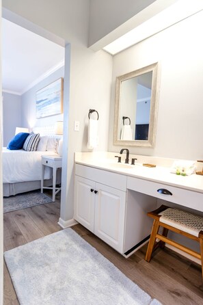 A modern bathroom with a white vanity, a large mirror, and a wooden stool. - Beach Please Condo Beach View (Rosemary Beach)