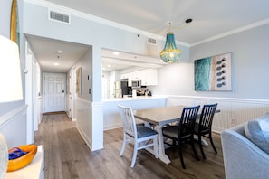 A modern kitchen with white cabinetry, a central island, and a hanging pendant light. - Beach Please Condo Beach View (Rosemary Beach)