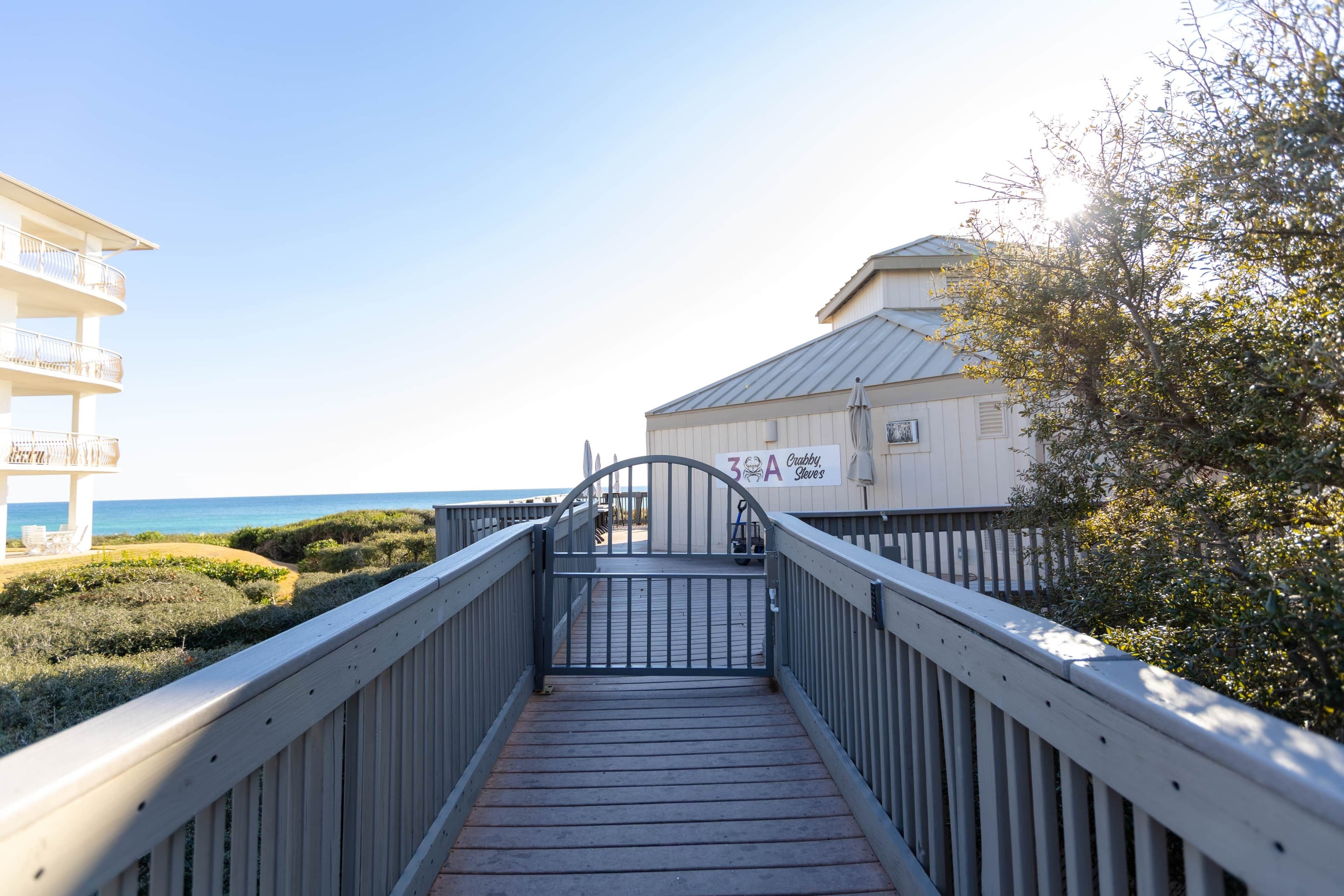 Un puente de madera que lleva a una playa, con un edificio en el fondo identificado como "Crabby Slaves".
