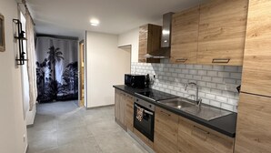A modern kitchen with wooden cabinets, a black countertop, a stainless steel sink, and a built-in oven.