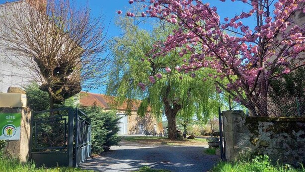 Un camino rural que lleva a una entrada con portón y un cartel que indica una casa rural, Gîte.