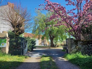 A rural pathway leading to a gated entrance with a sign indicating a Gîte.