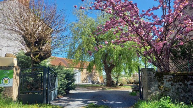 A rural pathway leading to a gated entrance with a sign indicating a Gîte hotel. - Charming cottage with garden and pets allowed in Allier (Buxières-les-Mines)