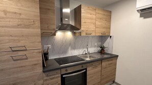 A modern kitchen with wooden cabinets, a stainless steel sink, and a built-in oven. - Charming cottage with garden and pets allowed in Allier (Buxières-les-Mines)