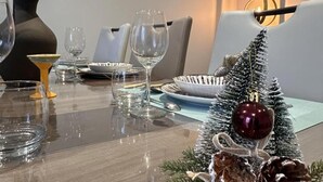 A dining table set with clear glassware, plates, and a small Christmas tree with ornaments. - Charming cottage with garden and pets allowed in Allier (Buxières-les-Mines)