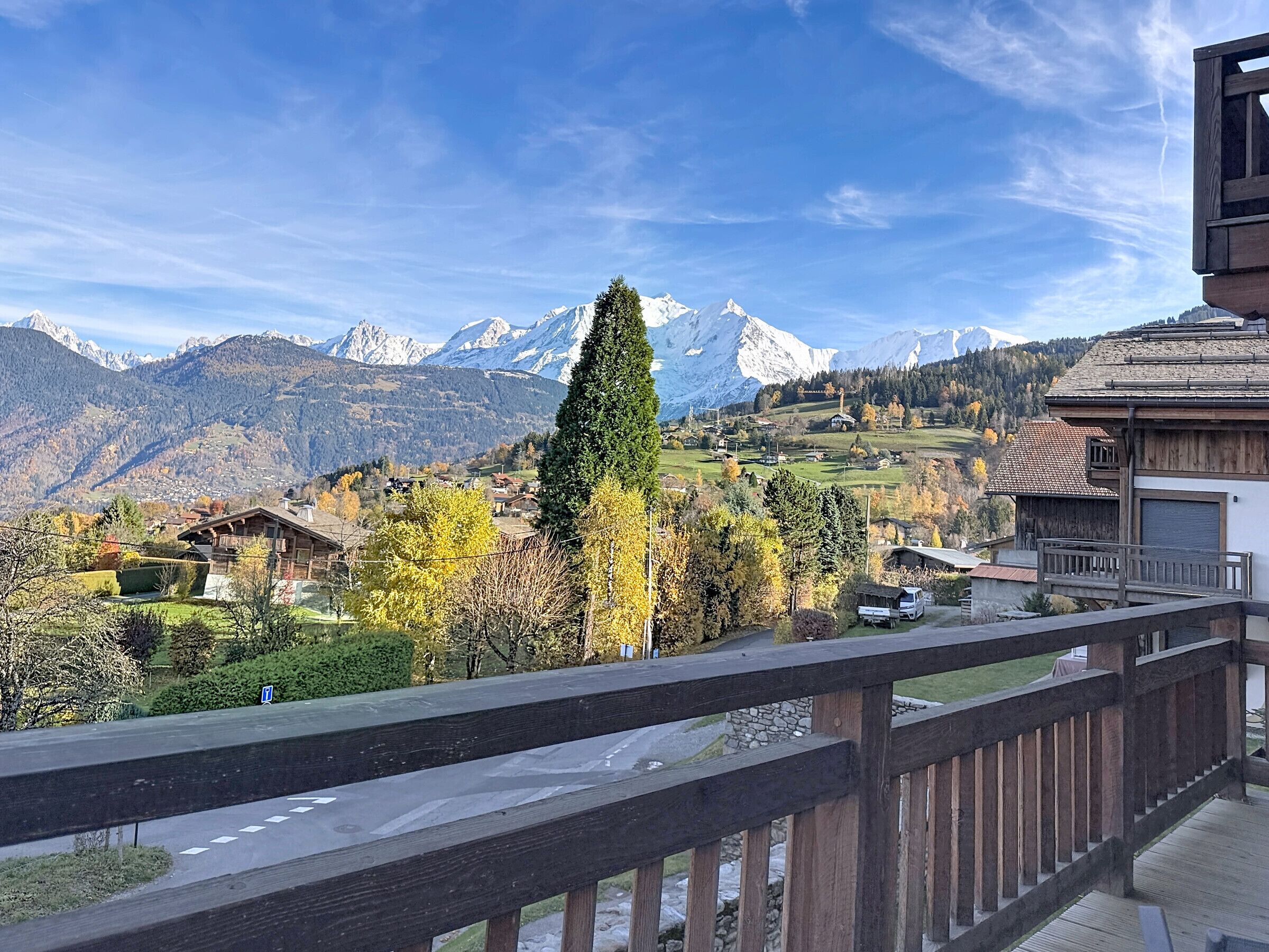 A mountain landscape with snow-capped peaks, a wooden building with a balcony, and a clear sky.