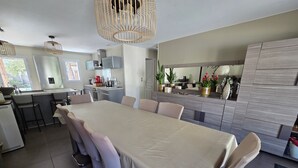 Una cucina moderna con zona pranzo, caratterizzata da un tavolo grande, sgabelli da bar e forno integrato.