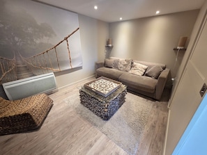 Ein modernes Wohnzimmer mit einer Couch, einem Couchtisch, einem Teppich und einem Wandlautsprecher.