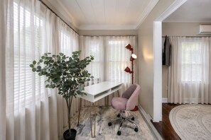 A room with a white desk, a pink chair, a potted plant, a floor lamp, and a round rug. - Historic Uptown 2BD 1BA - 8 min to Downtown & Pier (St. Petersburg)