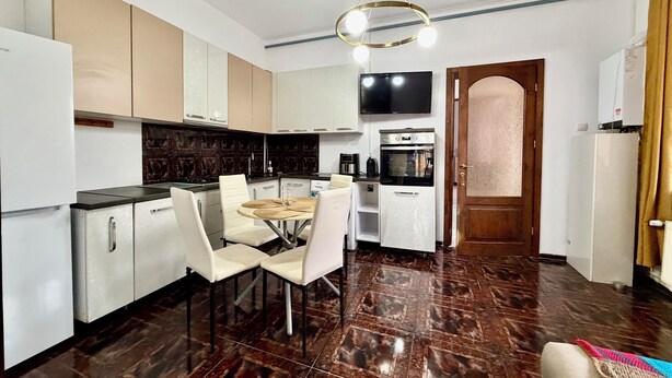 A compact kitchen with modern appliances, a dining area with a round table and chairs, and a large mirror above the oven. -  Accommodates up to 6 guests,Free parking,Near Amazonia Aquapark,Iulius Town (Timișoara)