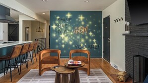 Una cocina moderna con barra, sillas de madera y una pared con texto motivacional.