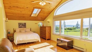 Un dormitorio con cama, cómoda de madera y un ventanal con vistas.