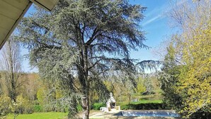 Un jardin avec une piscine, un kiosque et un grand arbre.