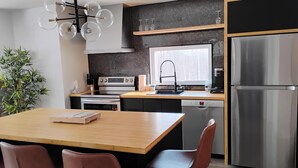 Eine moderne Küche mit einer Holzinsel, Edelstahlgeräten und einer schwarzen Spritzschutzwand.