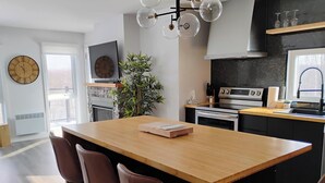 Eine moderne Küche mit einer Holztheke, Edelstahlgeräten und einer großen Wanduhr.