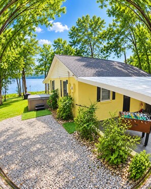 Una casa amarilla con un patio, mesa de fútbol de mesa y vistas a un lago.