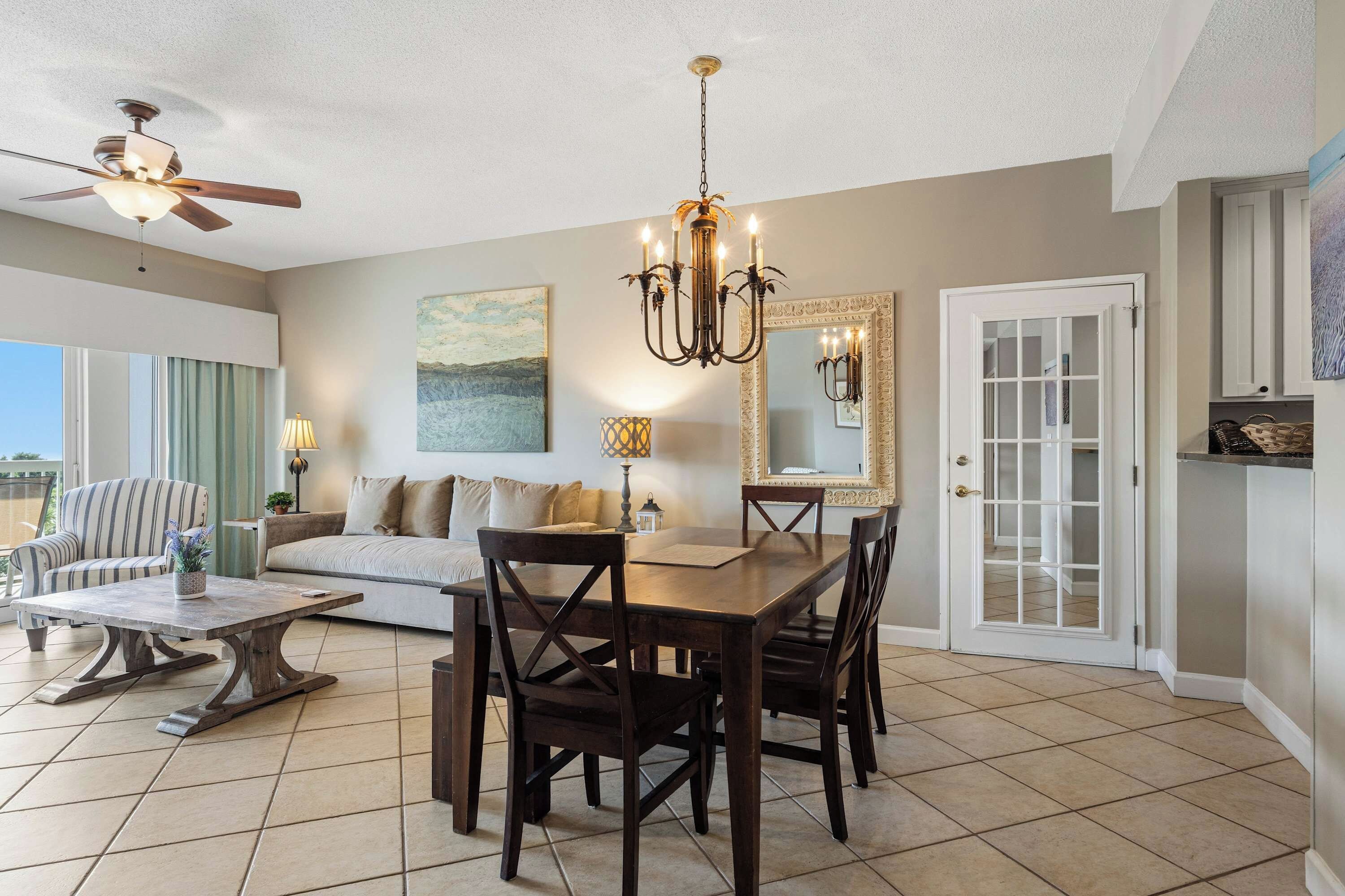 A spacious living room with a dining area, a ceiling fan, and a large window.