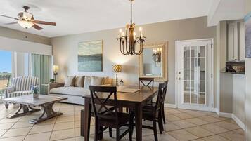 A spacious living room with a dining area, a ceiling fan, and a large window.