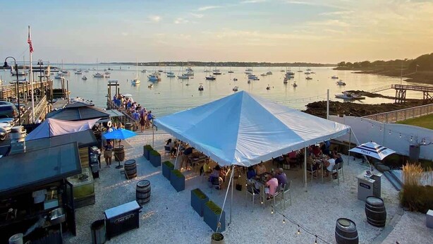 A marina with boats, a large tent, and outdoor seating areas. - Fresh + Modern Garden Level Kittery Studio (Kittery)