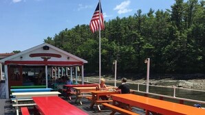 A wooden deck with picnic tables and a covered seating area. - Fresh + Modern Garden Level Kittery Studio (Kittery)