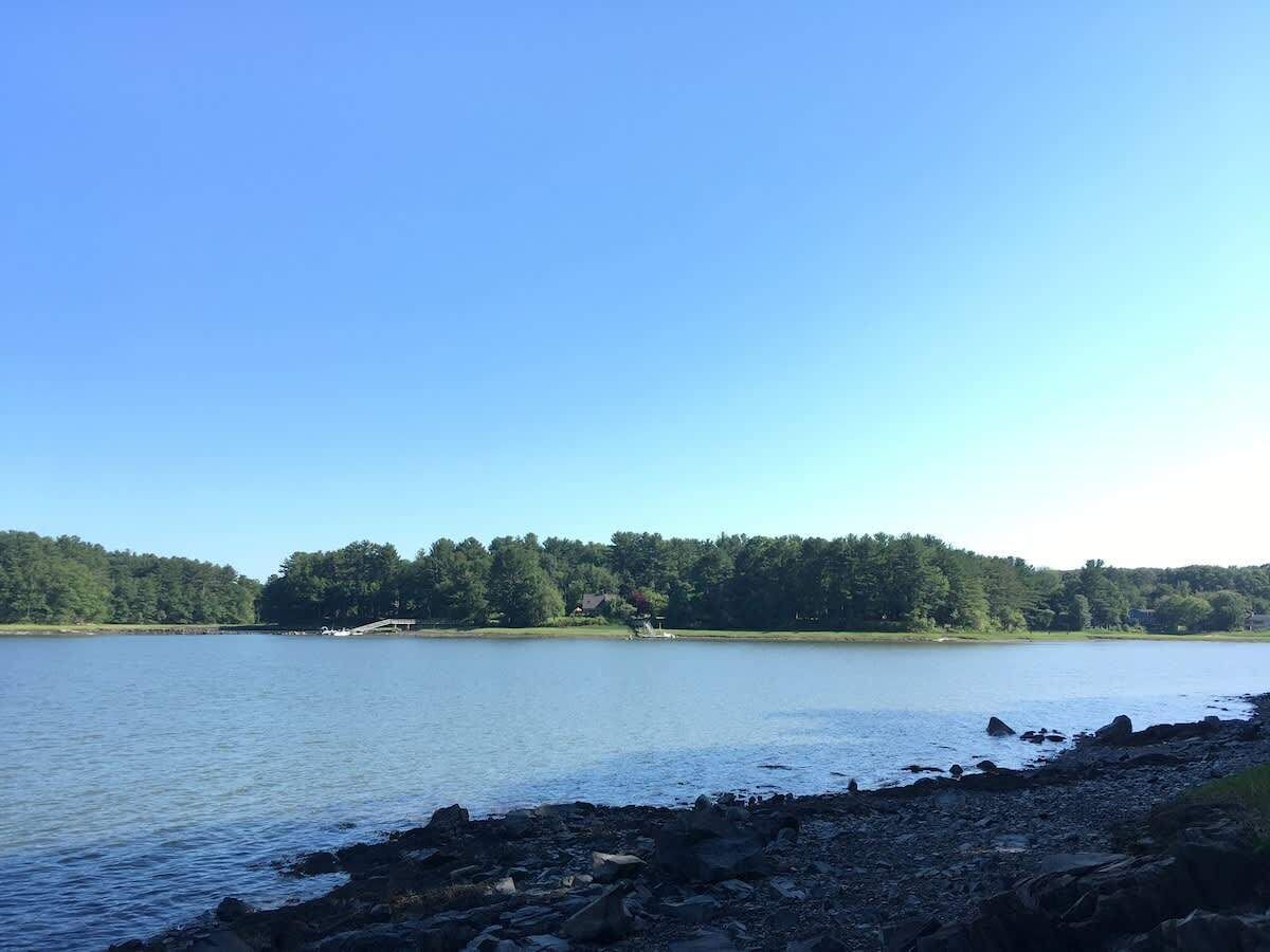 Un lac aux rives rocheuses, avec une zone boisée en arrière-plan.