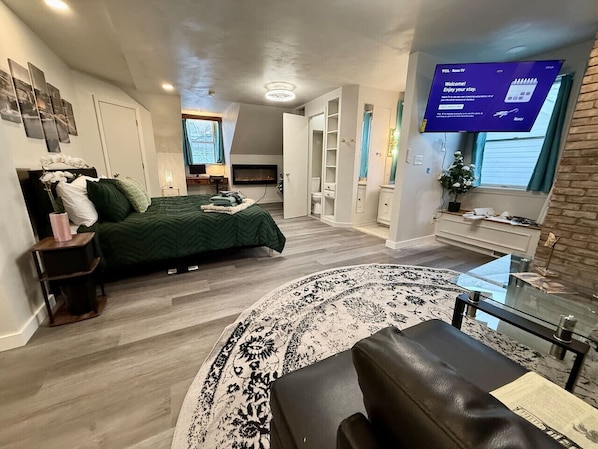Een moderne hotelkamer met een bed, een televisie, een open haard en een groot raam.