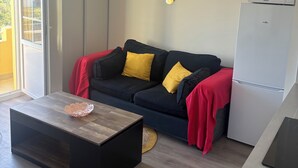 Un salon moderne comprenant un canapé, une table basse, un four à micro-ondes et un réfrigérateur.
