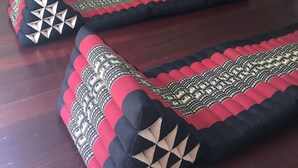 Una habitación con piso de madera oscura y un sofá con estampado rojo y negro.